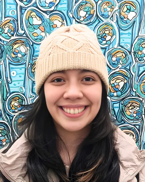 A smiling Unicorn in a knit beanie in front of a colorful mural